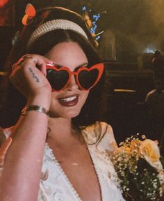 a woman wearing heart shaped sunglasses and holding flowers