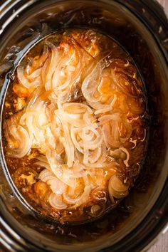 the food is being cooked in the crockpot with noodles and broth on top