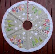 a christmas tree skirt made out of fabric on a wooden deck with red and white trim