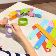 a child is cutting up pieces of colored paper with scissors on a white tablecloth