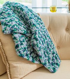 a blue and green crocheted blanket sitting on top of a couch