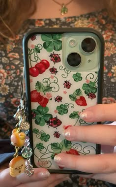 a woman holding an iphone case with flowers and ladybugs on it