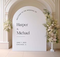 an arch decorated with white flowers and greenery is the backdrop for a wedding ceremony