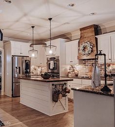 a kitchen with white cabinets and an island in front of a stove top oven next to a refrigerator