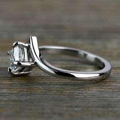 an engagement ring with a princess cut diamond in the center on top of a wooden table