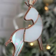 an ornament shaped like a deer hanging from a christmas tree with lights in the background