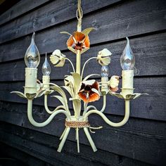 a chandelier hanging on the side of a building with flowers and leaves painted on it