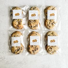 six chocolate chip cookies wrapped in plastic on a white countertop, with labels for each cookie