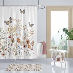 a bathroom with a shower curtain decorated with flowers and butterflies, along with a rug on the floor