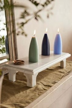 three candles sitting on top of a table next to a mirror