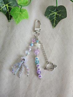 a keychain with beads and charms attached to it sitting on a table next to a plant