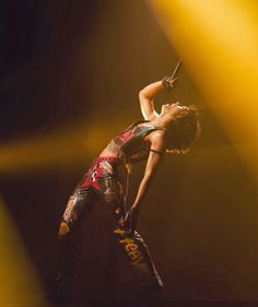 a woman is performing on stage with her hands in the air while holding a microphone