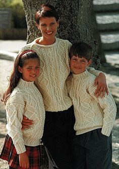 two children and an adult standing in front of a tree with their arms around each other