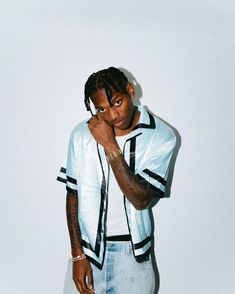 a man with dreadlocks standing in front of a white wall