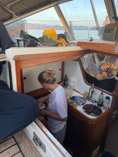 the woman is washing dishes in the sink on the boat