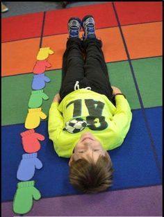 a young boy laying on the ground in front of a rainbow colored floor with his feet up