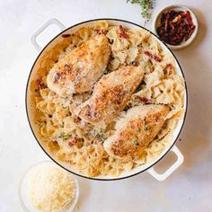 chicken and pasta with parmesan cheese in a pan on a white counter top