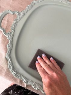 a person wiping down a plate with a cloth on it and a hand holding a sponge