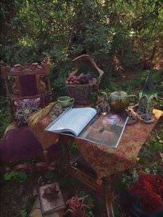 an open book sitting on top of a table in the middle of some bushes and trees