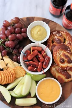 a platter with pretzels, grapes, apples, crackers and other snacks