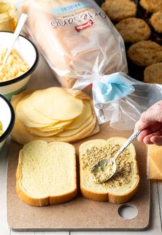 a person is spreading cheese on bread with butter and other food in the background,