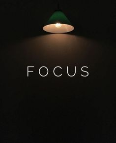 the word focus is lit up in front of a black wall with a green lamp