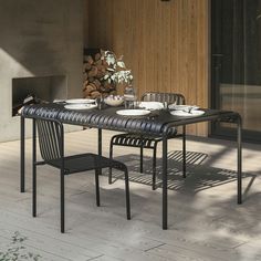 an outdoor table with two chairs and plates on it in front of a fire place