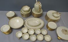 a table topped with lots of white and gold dishes