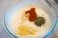 ingredients in a glass bowl on a white counter top, including spices and seasoning