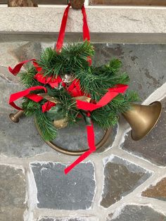 a bell with a red ribbon around it and a christmas wreath on the front door