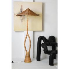 a lamp that is sitting next to a chair and painting on the wall behind it