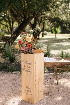 a wooden box with flowers in it sitting on the ground next to a park bench