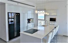 a modern kitchen with white cabinets and counter tops, along with an island in the middle