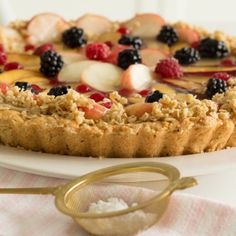 a close up of a pie on a plate with berries and other toppings next to a pair of scissors