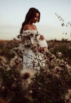 a pregnant woman standing in a field of flowers