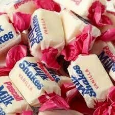 pink and white candy sticks are piled on top of each other