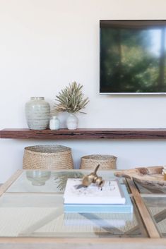 a living room with a glass coffee table and vases on the shelf above it