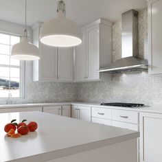 a kitchen with white cabinets and an island in front of the stove top is filled with fruit