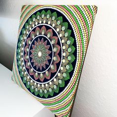 an artistically designed pillow sitting on top of a white table next to a wall