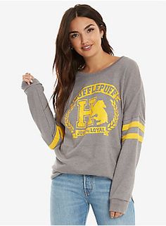 a woman wearing a grey and yellow sweatshirt with the letter h in gold on it