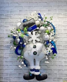 a white elephant with blue and green decorations on it's head hanging from a brick wall