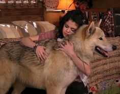 a woman holding a large dog on top of a bed