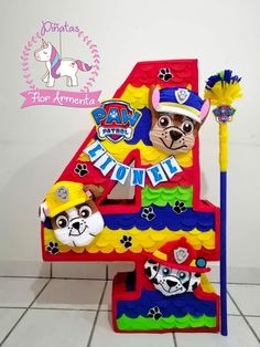 the number four is made out of paper and has paw patrol characters on it, as well as a broom