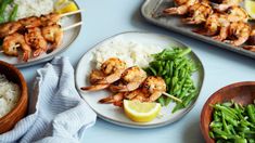 shrimp and rice are served on skewers with lemon wedges, as well as green beans