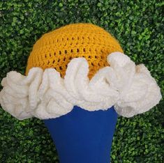 a crocheted hat with white ruffles on it sitting on top of a blue vase