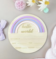 a wooden plaque with the words hello world and rainbows on it next to flowers