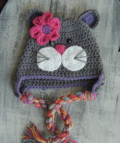 a crocheted bear hat with a flower on the top and a rope attached to it