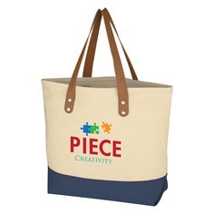 a canvas tote bag with leather handles and two contrasting sides, featuring the piece creativity logo