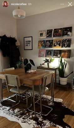 a dining room table and chairs in front of a wall with pictures on the walls