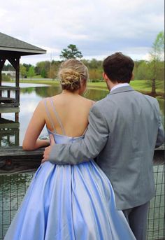 a man and woman standing next to each other in front of a body of water